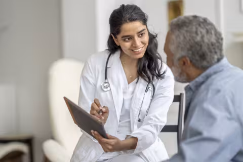 healthcare provider holding tablet talking to patient