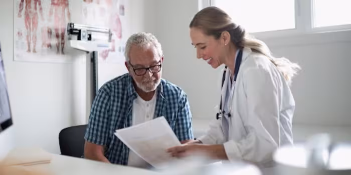 woman in white jacket reviewing paper with man in glasses